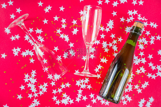 新年和圣诞节假期布局带眼镜和一瓶香槟和白色五彩纸屑的时尚亮粉色背景顶图片
