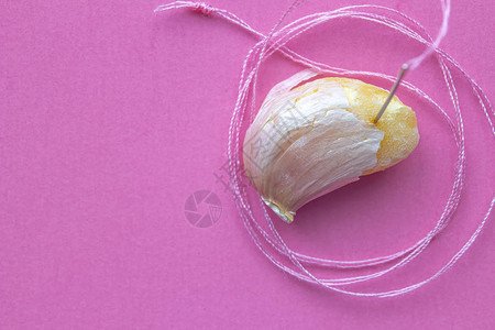 一个带缝纫针的大蒜和一个粉红色的粉红色缝纫线轴图片