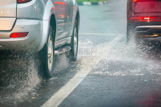 雨水从银色和红色汽车的轮上飞溅出来图片