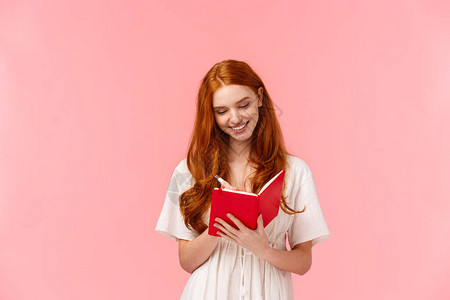 可爱感时尚的红发女孩在可爱的红色笔记本上制作清单学习写作业或日程安排图片