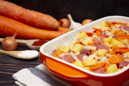 在橙色烤盘中切片肉洋葱胡萝卜和土豆橙色烤盘中蔬图片