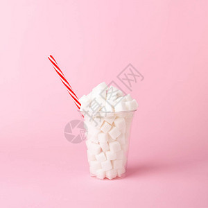 粉色糊面底部的塑料玻璃和满是糖块的吸管不健康的饮料概念最小垂图片