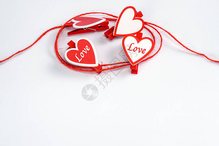 用红色和白色衣夹在白色背景上的心形滚红色绳子情人节的概念带有文本或广告复图片