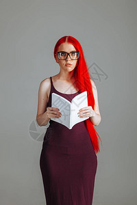 红长头发女孩戴眼镜带白书展示品的图片
