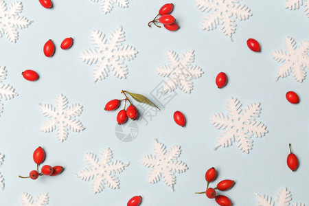 圣诞图案由浅蓝色背景上的雪花和红色浆果制成圣诞节寒背景图片