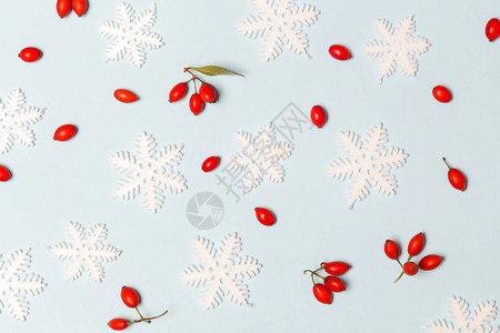 圣诞图案由浅蓝色背景上的雪花和红色浆果制成圣诞节寒背景图片