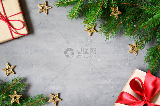 圣诞礼物与红丝带在灰色背景的框架中由冷杉树枝与星图片