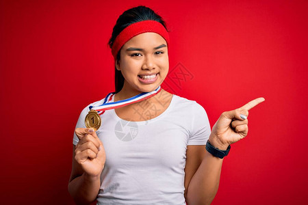 年轻的亚洲冠军女孩站在孤立的红色背景上赢得奖牌图片