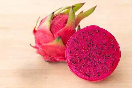 新鲜的火龙果在木质背景上切片或成熟的火龙果红色背景图片