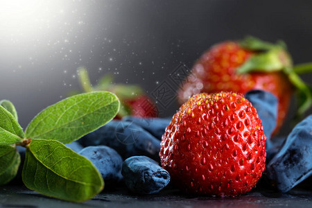 黑暗的蜜莓和深色背景的甜草莓图片