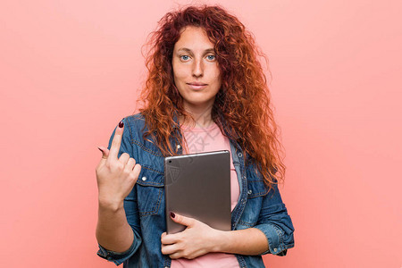 年轻的天主教红头发女人拿着平板电脑用手指着你好像邀请图片