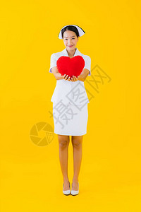 美丽的年轻的亚洲年轻女泰文护士显示心脏枕头形状图片