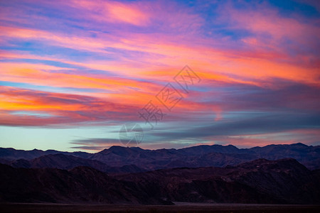 剪影山峰和紫色山脊的一个惊人的日落或日出场面与暮色背景蓝天和桃红图片