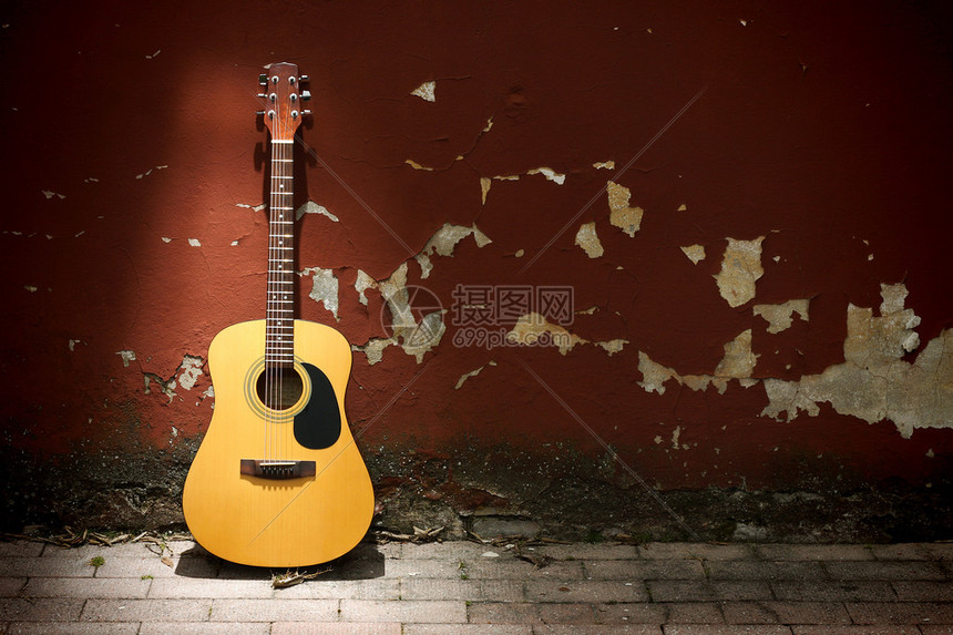 靠在又脏臭的墙上的原声吉他图片