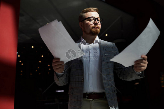 在筹备公共活动时站在黑暗房间的舞台上和阅读论文上图片