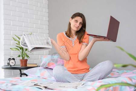 女孩在报纸的帮助下或在互联网上的笔记本电脑的帮助下图片