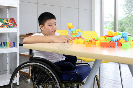 坐在轮椅上玩彩色塑料块构造玩具图片