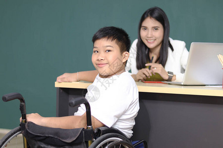 残疾儿童教室坐在轮椅上的男孩与老师儿童学习和在学校图片