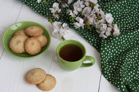 一杯绿色餐巾上的黑茶土制饼干白底的杏图片