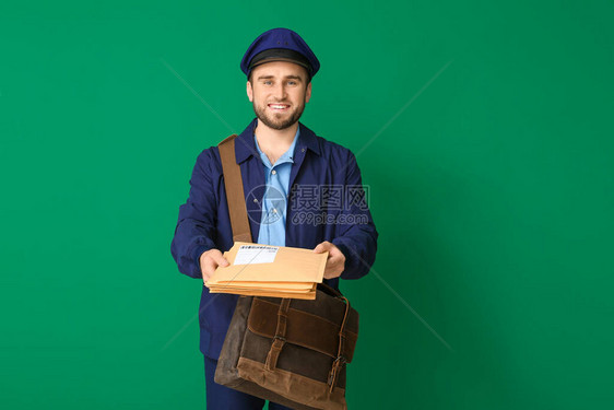 颜色背景的英俊的年轻邮递员图片