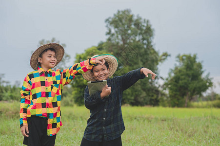 两个亚裔男孩使用平板站在外面的门外农民概念智能农民或教育图片