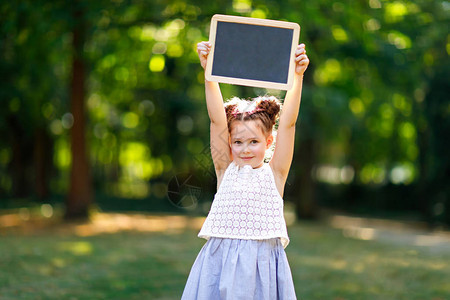 快乐的小女孩手里拿着空的粉笔桌小学第一天的小学生户外健康可爱的孩子图片
