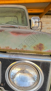 一辆古老绿色汽车的肮脏和生锈外表前方的垂直边框图片