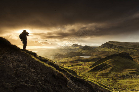 摄影师在英国苏格兰高地斯凯岛拍摄Quiraing山风景的剪影日出时间与背景中五颜六色的ra背景图片