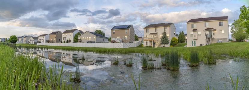 在一片草地和闪亮的池塘前建造的美丽多层房屋图片