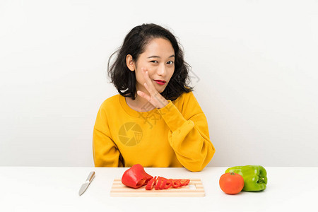 有蔬菜的年青亚洲女孩坐在桌子上悄图片