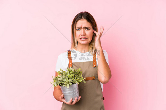 年轻的caucasian园丁女人在粉红色背景用图片