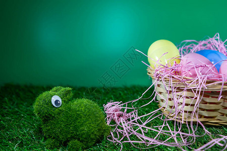 带草的篮子上的复活节彩蛋和用绿色背景的草制成的绿色图片