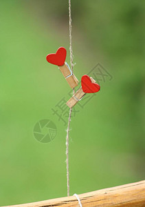两个衣服挂着一颗红色的心挂在网上与草的绿色背景情背景图片