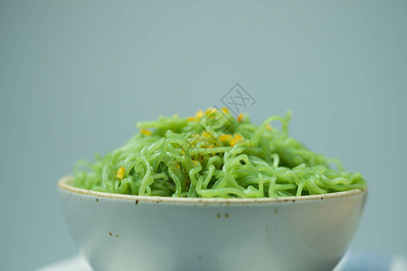 准备上菜的白色陶瓷碗中的绿色面条特写图片