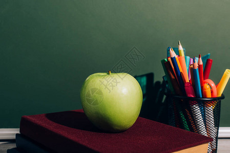 整个苹果放在笔架附近的书本上背景图片
