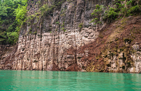 大宁河上的迷你三峡多色棕和灰色岩石峭壁特写镜头在翡翠绿水之图片