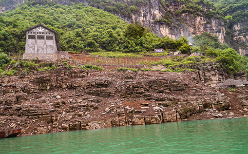 迷你三峡灰色的水泥谷仓建在大宁河棕色石头海岸线上图片