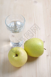 青苹果和木制背景上的一杯饮用图片