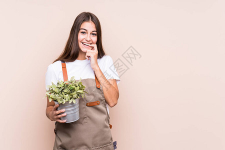 年轻的园丁白种人妇女拿着一株孤立的植物放松地思考着看复图片