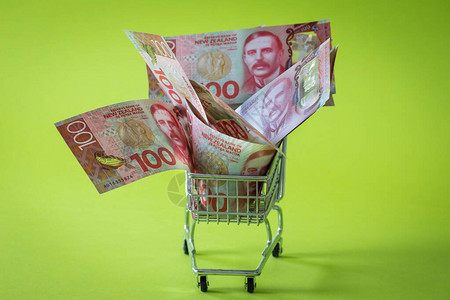 有新西兰百元钞票的微型购物车购物的概念背景图片
