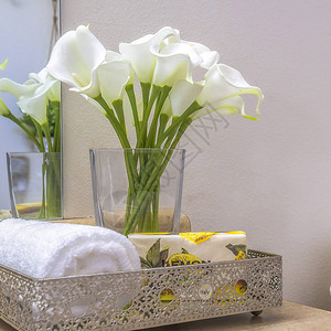 SquareTowels鲜花和纸巾放在浴室马桶旁边的台面上在这个洁净室内还可以看到白色的墙壁图片
