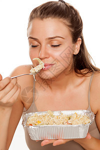 一个年轻快乐的女人闻着食物的味道以图片