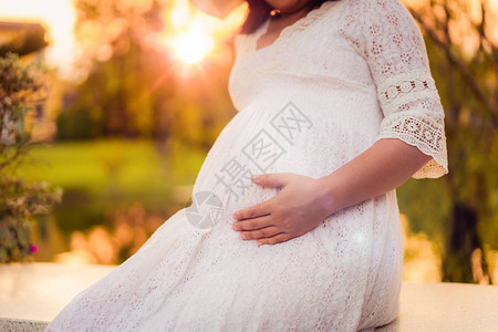 孕妇在照顾孩子的同时对花园住宅的新生活感到满意年轻的准妈抱着婴儿在怀孕的肚子里产前护理和图片