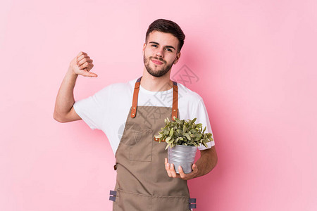 年轻caucasian园丁男子持有一个孤立的植物图片