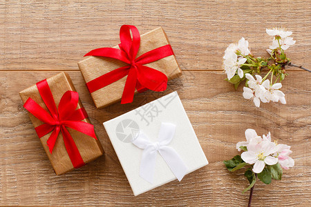 配有花樱树枝的礼品盒在木质背景上顶端视图在节假日赠图片