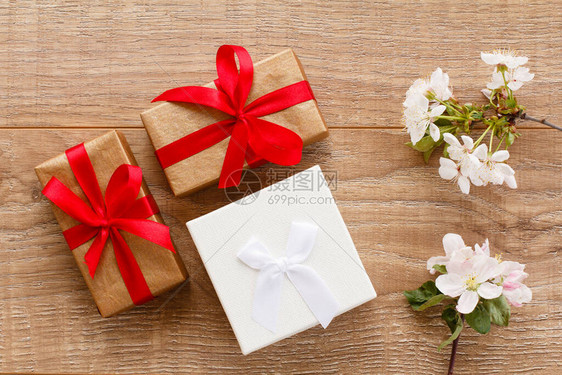 配有花樱树枝的礼品盒在木质背景上顶端视图在节假日赠图片
