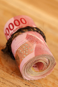 身份证,印尼钞票卷成一个管子面值为100000的idr钞票在旧木背景上用