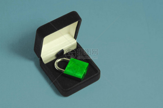 锁定礼品盒珠宝箱中带有闭合卸扣的绿色挂锁安全或保护软件或硬件的概念订婚或礼或婚姻的象征图片
