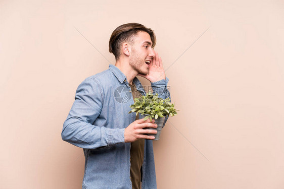 年轻caucasian男子拿着植物喊叫图片