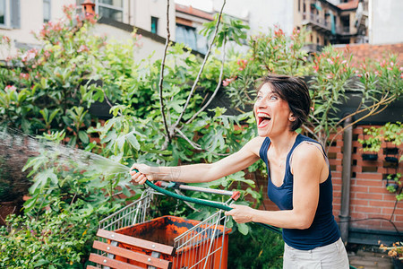 中年妇女户外露台园艺浇水植物笑得开心图片
